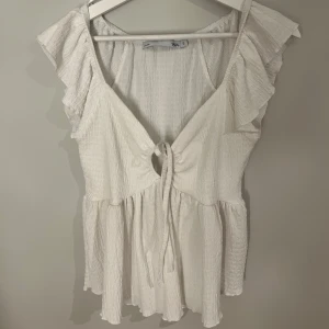 Vit blus med volangdetaljer - Säljer en söt vit blus från Lager 157 med volangdetaljer och knytning framtill, använd en gång