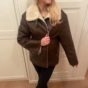 Brun skinnjacka från Gina tricot med mysigt foder - Snygg brun jacka i skinn imitation med mjukt vitt teddyfoder och dragkedja. Perfekt för kyligare dagar med sin varma och stiliga design. Jackan har en klassisk look med en bekväm passform. Helt slutsåld hos Gina Tricot.