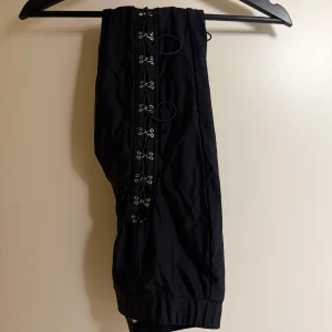 Svarta byxor med snörning från Forever 21 - Snygga svarta byxor från Forever 21 med cool snörningsdetalj framtill. Perfekta för en trendig look.