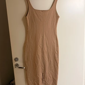 Beige klänning från Zara Trafaluc - Säljer en stilren beige klänning från Zara Trafaluc, perfekt för vår och sommar. Klänningen har en tight passform med smala axelband och en liten slits framtill. Tillverkad i ett mjukt material som ger en bekväm känsla.