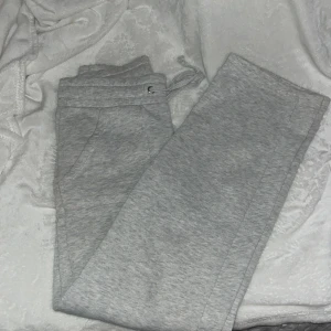 Grå mjukisbyxor med snörning - Säljer ett par grå mjukisbyxor med snörning i midjan. Byxorna har en bekväm passform och är perfekta för en avslappnad stil. De har fickor både fram och bak. De har ett litet hål på sidan av benet men absolut inte uppmärksammt