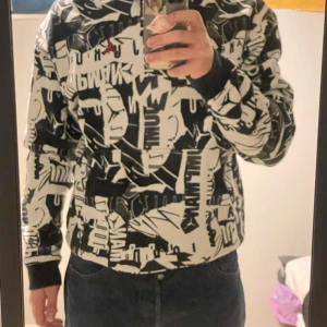 Svartvit mönstrad hoodie från Jordan - Säljer en cool svartvit hoodie från Jordan med ett unikt grafiskt mönster och den ikoniska röda Jumpman-loggan. Hoodien har långa ärmar och en dragkedja framtill. Perfekt för streetwear-stilen!