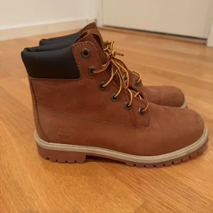 Bruna boots från Timberland - Säljer ett par klassiska bruna boots från Timberland med snörning och robust sula. Perfekta för höst och vinter med sitt slitstarka skinnmaterial och bekväma passform.