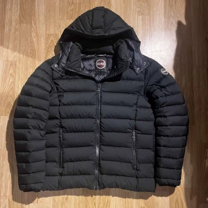 Svart pufferjacka från Colmar - Snygg svart pufferjacka från Colmar med huva och dragkedja. Perfekt för kyliga dagar. Jackan har en quiltad design och är både stilren och funktionell. Storlek 52 men passar M perfekt. Priset kan diskuteras, hör av dig vid funderingar!