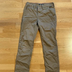 Bruna chinos från Vans - Snygga bruna chinos från Vans med klassisk design. De har en normal passform och är tillverkade i bomull. Byxorna har både fram- och bakfickor samt en knapp och dragkedja i gylfen.