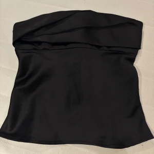 Svart tubtopp från Zara - Svart topp i nyskick. Satinmarerial, dragkedja bak. 