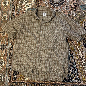 Brunrutig kortärmad skjorta - Säljer en brunrutig kortärmad skjorta med knappar och en bröstficka. Perfekt för en avslappnad stil.