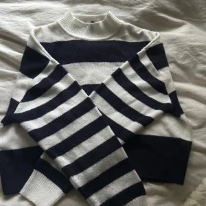 Randig tröja från H&M - Säljer en snygg randig tröja från H&M i mörkblå och vit. Tröjan har långa ärmar och en klassisk rund halsringning. Tröjan är åt det lite kortare hållet men mysig på en sommarkväll.☺️🫶🏻