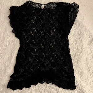 Svart spetsblus från Vila - Snygg svart spetsblus från Vila i storlek XS. Blusen har ett vackert spetsmönster och korta ärmar. 