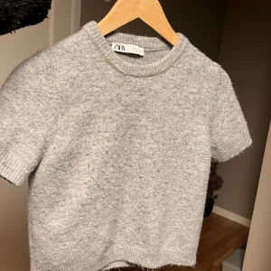 Grå stickad tröja från Zara - Hej! Säljer en stickad tröja med korta ärmar ifrån zara, tröjan har använts fåtal gånger då den blivit för liten. Skriv gärna om ni har några funderingar om tröjan!. 