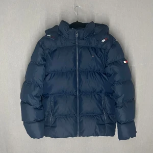 Tommy Hilfiger Jacka - Snygg  pufferjacka från Tommy Hilfiger i storlek 176, passar S/M. Skick är 7/10 pga lagningen nere på vänstra ärmen. Skriv för fler bilder eller vid funderingar 🙌😁