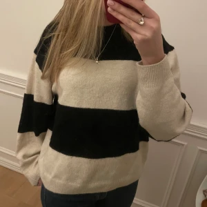 Randig sticker tröja - Säljer en mysig randig tröja i beige och svart med långa ärmar. Perfekt för kyligare dagar och passar bra till jeans. Tröjan har en avslappnad passform och är gjord i ett mjukt material.