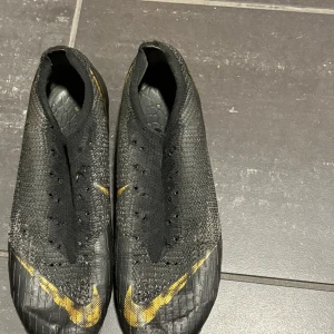 Svarta fotbollsskor från Nike - Säljer ett par svarta fotbollsskor från Nike med gula detaljer. Skorna är i ett acceptabelt skick men dock inga sulor eller skosnören