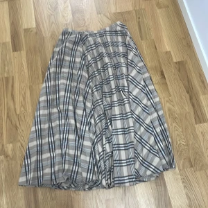 Rutig kjol från H&M - Snygg rutig kjol från H&M i beige och svart. Kjolen har en klassisk design med ett tidlöst rutmönster och är perfekt för både vardag och speciella tillfällen. Den är gjord i ett lätt och bekvämt material som ger en fin passform.