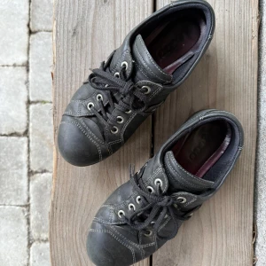 Svarta sneakers med snörning - Säljer ett par svarta sneakers med snörning och dekorativa sömmar. Skorna har en låg profil och en bekväm sula, perfekt för vardagsbruk.