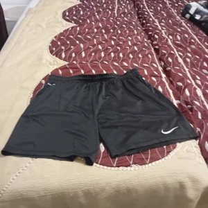 Svarta träningsshorts från Nike - Säljer ett par svarta träningsshorts från Nike med Dri-Fit-teknologi. Perfekta för sport och träning med en bekväm passform och elastisk midja.