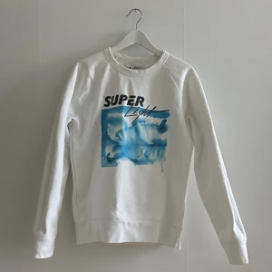 vit sweatshirt från Our Legacy - en vit sweatshirt från Our Legacy med trycket 'Super Light' i svart & blått. tröjan är i ett super tjockt bomulls tyg. 
