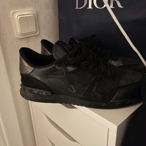  Valentino rockrunners  - Snygga svarta sneakers från Valentino med diskreta detaljer och snörning. Perfekta för en stilren look. Skorna är i storlek 42 och skulle säga skicket på dem är 7,5/10 finns inga stora skador bara småa repor omkring skorna. Har tyvärr ingen box, köpte skorna utan box!!