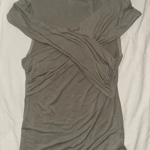 Grön Festtopp  - Grön festtopp från Gina tricot. Den mer gråare ut på bild än vad den är i verkligheten. Toppen har en smickrande passform och är lätt att styla för olika tillfällen.