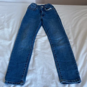 Blå jeansbyxor - Snygga blå jeansbyxor med klassisk femficksdesign och knappgylf. Perfekta för en avslappnad stil. De har en rak passform och är tillverkade i ett slitstarkt denimtyg.
