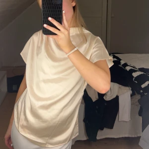 Beige blus - Elegant beige blus med korta ärmar och en mjuk, flytande passform. Perfekt för en stilren look. ( vet inte vart toppen kommer ifrån då den är köpt på Plick)