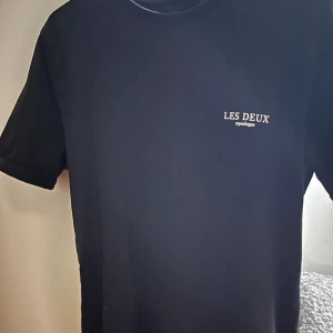 Svart t-shirt från Les Deux - Snygg svart t-shirt från Les Deux med liten logga på bröstet. Perfekt för en stilren look. Passar S och är i mycket bra skick. 