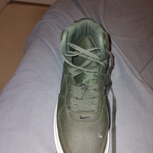 Gröna Nike Air sneakers med Gore-Tex - Snygga gröna Nike Air sneakers med Gore-Tex material. Skorna har snörning och en robust sula, perfekt för alla väder. Den klassiska Nike-loggan syns på sidan och tungan.