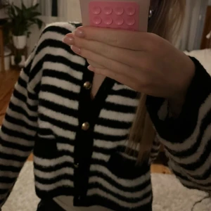 Svartvit randig kofta med guldknappar - Säljer en mysig svartvit randig kofta med guldknappar. Koftan har långa ärmar och två fickor framtill. Helt ny men lappen är bortttagen! Den är i stl. m men funkar som en s