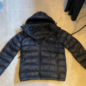 Svart dunjacka från Peak Performance - Säljer en svart dunjacka från Peak Performance. Jackan har en dragkedja framtill och är långärmad med en quiltad design. Denna Jacka ny kostar ungefär 2000kr så detta är en super deal! Perfekt för kyliga dagar med sin varma och bekväma passform. 🖤 Notera också att den är lagad på på två ställen men syns knappt när man har på sig den.