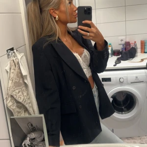 Svart kavaj - Snygg svart kavaj med klassisk design och knappar framtill. Perfekt för en stilren look. Passar bra över en topp eller blus.