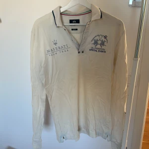 Vit långärmad pikétröja från La Martina - Säljer en stilren vit långärmad pikétröja från La Martina med broderade detaljer och text på bröstet. Tröjan var väldigt dyr i inköp men har inte använt den på några år.  Behöver en tvätt och strykning. Det är en Large slimfit.