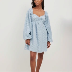 Ljusblå klänning med blommigt mönster - Säljer en söt ljusblå klänning från NA-KD med blommigt mönster. Klänningen har långa ärmar och en v-ringad design. Perfekt för vår och sommar! 🌸