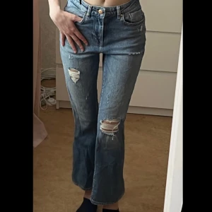 Blå ripped jeans - Mellanblå straight leg jeans med revor/slitningar, använd fåtal gånger fint skick, strl XS