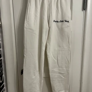 Vita mjukisbyxor från Pretty Little Thing - Snygga vita mjukisbyxor från Pretty Little Thing med broderad logga. Perfekta för en avslappnad stil. Byxorna har en bekväm passform och elastisk midja. Aldrig använda!