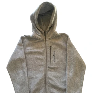 Bowman Zip från Sail Racing - Bowman zip hoodie från Sail Racing med dragkedja och justerbar huva. Tillverkad i en mjuk blandning av bomull och polyester.              Orginal pris 1500kr