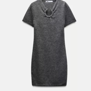 Grå klänning från Zara - Snygg grå klänning från Zara i en tight passform. Klänningen har korta ärmar och en unik detalj vid halsringningen. Perfekt för en stilren look.