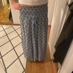 Blå långkjol - Säljer en jättesöt och somrig blå långkjol med ett snyggt mönster och knytband med tofsar i midjan. Är helt som ny. Säljer då den tyvär har blivit för kort för mig själv är jag 174 och kjolen är i storlek 170 