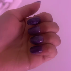 Lila nagellack med glittereffekt - Snyggt lila nagellack med en glittrig finish som ger en trendig look. Perfekt för att ge dina naglar en extra touch av glamour. Lätt att applicera och ger en jämn täckning.