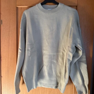 Beige stickad tröja - Säljer en stilren grön stickad tröja med rund hals och långa ärmar. Perfekt för kyligare dagar och enkel att matcha med olika outfits. Tröjan har en klassisk design med ribbade muddar vid ärmslut och nederkant.