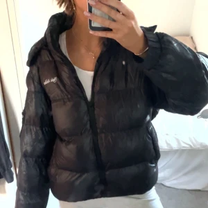 Svart pufferjacka från Night Addict - Säljer en svart pufferjacka från Night Addict. Jackan har en dragkedja framtill och en huva för extra värme. Perfekt för kyliga dagar. Den är långärmad och har en glansig yta. Kommer inte till användning då jag har andra jackor jag använder mer.😇 ordinarie pris är runt 700.