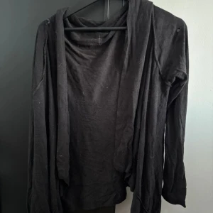 Svart långärmad kofta - Säljer en svart långärmad kofta i mjukt material. Perfekt för lager-på-lager och att hålla sig varm under kyliga dagar. Enkel och stilren design som passar till det mesta.