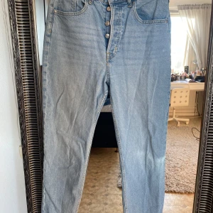 Blå jeans från H&M Divided - Snygga ljusblå jeans från H&M Divided med knappgylf och klassisk femficksdesign. Perfekta för en avslappnad stil.