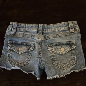 Blå jeansshorts från Gina Tricot - Snygga blå jeansshorts från Gina Tricot med knappar på fickorna, de är ändats använda ett fåtal gånger och är nästan som nya! De är 158 barn storlek men passar även xxs/xs
