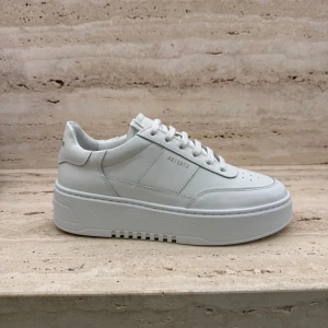 Vita sneakers från Axel Arigato - Stilrena vita sneakers i skinn från Axel Arigato med snörning och en tjock sula. Oanvända i storlek 37, men passar mig som vanligtvis har 38