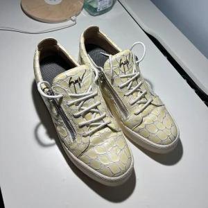 giuseppe zanotti skor - Snygga sneakers från Giuseppe Zanotti med ett unikt mönster och dragkedja på sidan. Skorna har vita snören och en bekväm sula. Perfekta för att ge din outfit en cool touch.