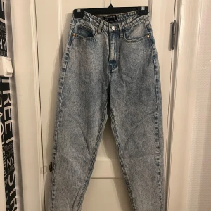 Blå mom jeans från PrettyLittleThing - Snygga blå mom jeans från PrettyLittleThing i denim. De har en hög midja och klassisk femficksdesign. Perfekta för en avslappnad stil med en vintage touch.