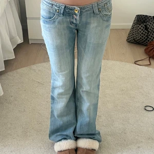 Lågmidjade bootcut jeans - Snygga ljusblå jeans med bootcut-stil och låg midja. De har en klassisk femficksdesign och en guldfärgad knapp framtill. Perfekta för en avslappnad look. Innerbenslängd: ca 78cm, midjemått: ca 37cm🌸🌸🌸