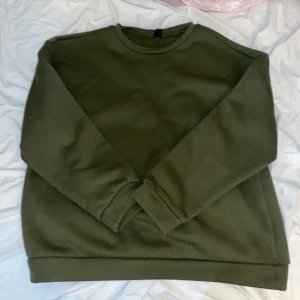 Olivgrön sweatshirt från Shein - Säljer en olivgrön sweatshirt från Shein med tryck på baksidan som säger 'Brooklyn 1898'. Tröjan har långa ärmar och en rund halsringning. Perfekt för en avslappnad stil.