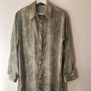 Zara klänning  - Leopardmönstrad skjortklänning med krage och knäppning framtill. Långa ärmar med manschetter. Storlek M. Strax över knäna på mih :) 