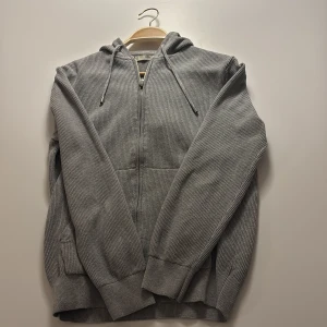 Grå stickad hoodie mango. - Säljer en stilren grå hoodie från MNG med dragkedja och huva. Tröjan är väl omhändertagen och i bra skick. Säljer pågrund av att den blivit förliten på mig.